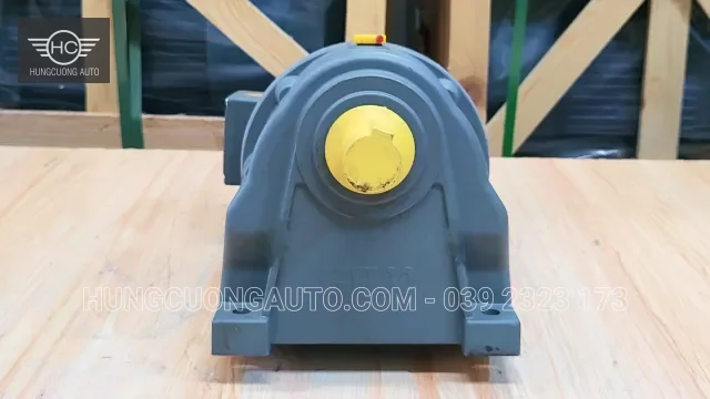Mặt trước hộp giảm tốc màu xám với nắp bảo vệ trục màu vàng.