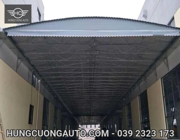 Mái bạt xám trên cao cùng hệ thanh giàn dọc hành lang giữa hai khối nhà